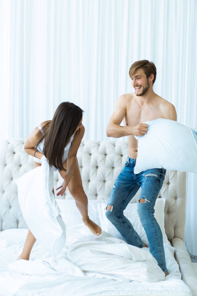Happy young couple is having fun in bed. Enjoying the company of each other. Pillow battle. - Fotoğraf, Görsel