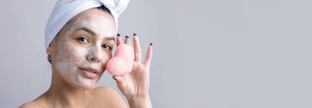 Szépség portré egy nő fehér törölköző a fejen egy szivaccsal egy test, tekintettel a rózsaszín szív. Bőrápolás öko-organikus kozmetikai spa relaxációs koncepció. - Fotó, kép