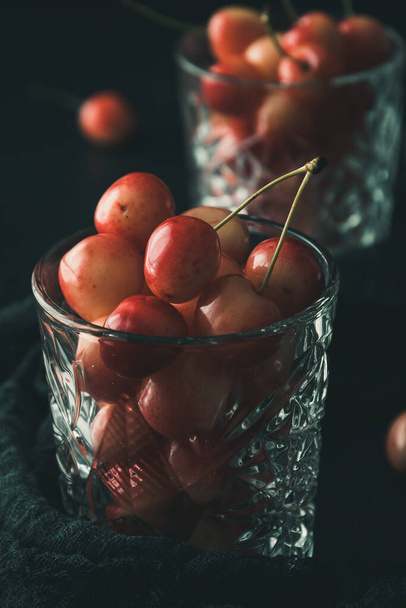 Ripe orange sweet cherries of sort 'royal anne' in a glass on black background, closeup - Фото, изображение