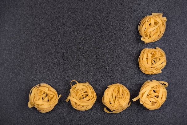 Spaghetti nesten op grijze achtergrond. Fettuccine of Tagliatelle. Koken achtergrond. - Foto, afbeelding