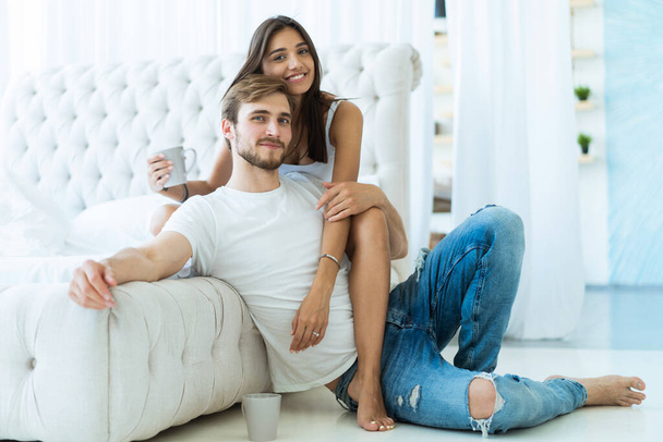 Loving young couple hugging and relaxing on sofa at home. - Zdjęcie, obraz