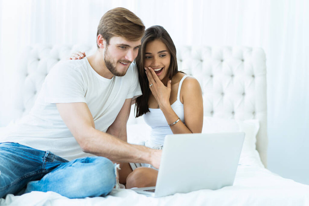 Young couple with laptop in the bed in room. - Foto, Bild