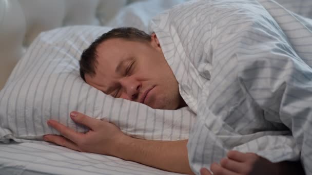Een man slaapt zoet in zijn bed, het concept van rust, gezonde slaap - Video
