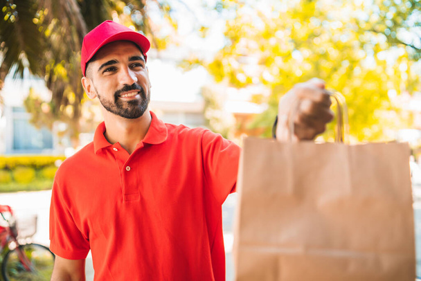 Portrait of a delivery man carrying packages while making home delivery to his customer. Delivery and shipping concept. - Foto, Imagen