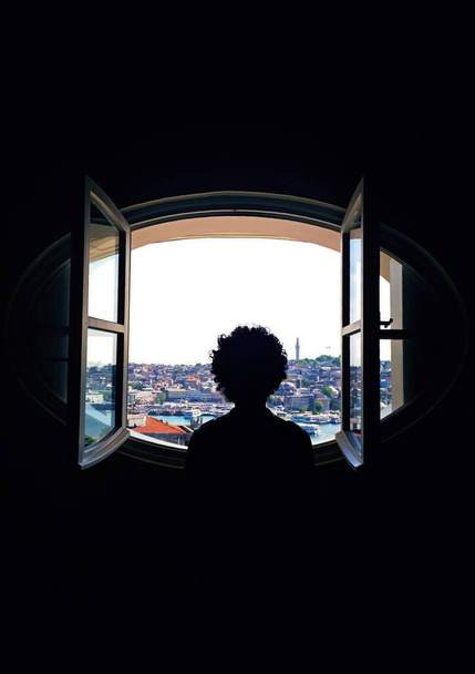 Человек, смотрящий в окно города. Человек сосредоточился на своих мечтах, глядя из города через окно
. - Фото, изображение