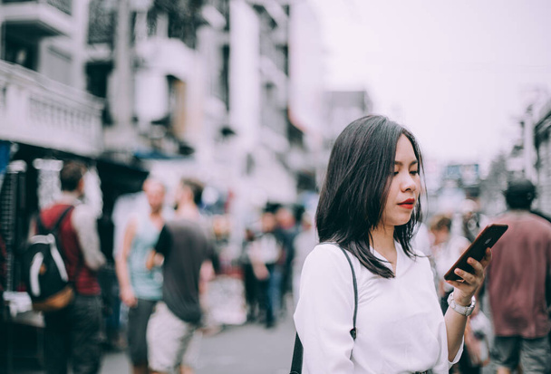 vista lateral de una joven jugando al teléfono móvil en la famosa calle de mochileros Khao San en Bangkok, Tailandia
 - Foto, Imagen