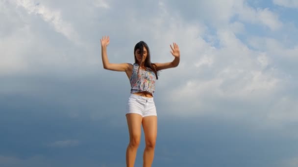 Szczęśliwa młoda piękna kobieta skacze, niebieskie tło nieba. 180 fps - Materiał filmowy, wideo