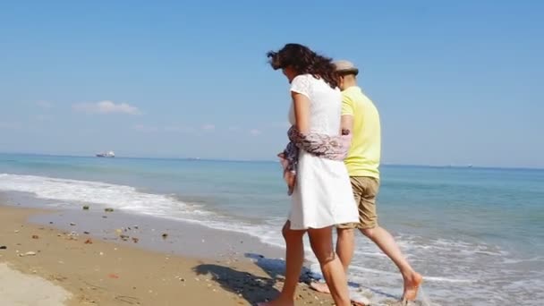 Romantik tatilde olan genç bir çift boş bir sahilde ağır çekimde yürüyor. - Video, Çekim