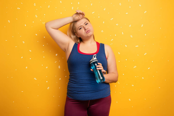 Fat girl does gym at home. tired expression. Yellow background - Foto, afbeelding