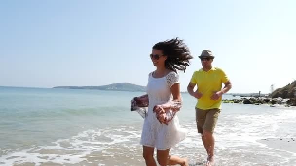 Młoda para na romantycznych wakacjach biegająca po pustej plaży, zwolnione tempo - Materiał filmowy, wideo