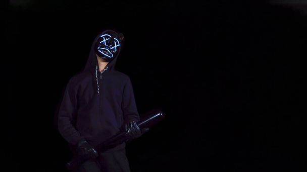 謎の光るマスクの野球バットを持つ男。黒の上に匿名のスイング - 写真・画像