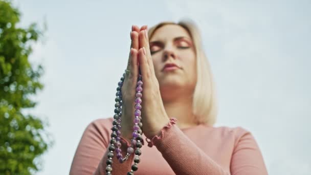 Womans hands with mala beads or rosary together symbolizing prayer and gratitude. Mudra. Yoga concept. Concentrated girl standing with hands in namaste and meditating or praying. - Materiaali, video
