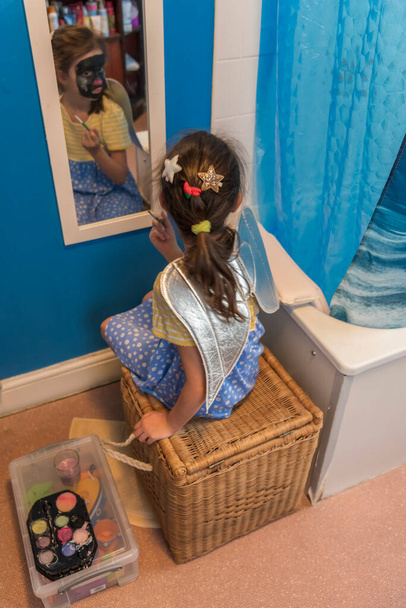 Молода дівчина з бідної сім'ї розважається живописом обличчя
 - Фото, зображення