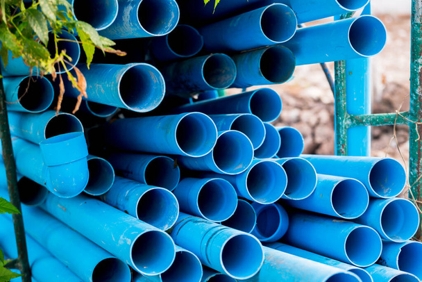 Selektivní na modré plastové potrubí pozadí. PVC trubky naskládané ve skladu staveniště. PVC vodovodní trubky používané pro stavbu. - Fotografie, Obrázek