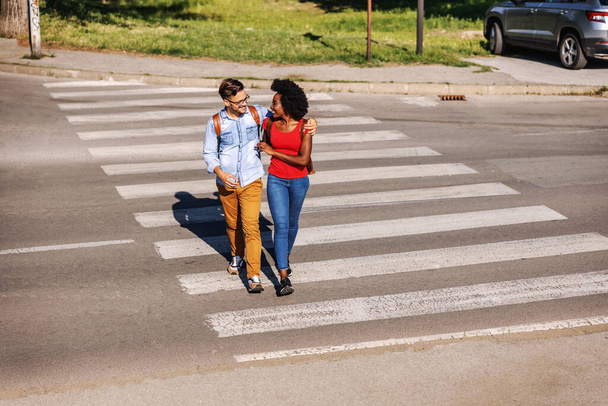 Young attractive multicultural happy hipster couple hugging and crossing street. - Foto, immagini