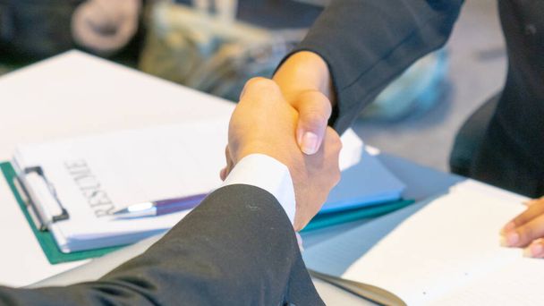 Geschäftsmann unterschreibt Vertragsdokument Partnerunternehmen und schüttelt Hand in Besprechungsraum. - Foto, Bild