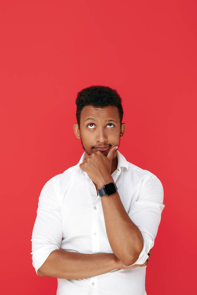 Confident african american young man thinking over red background. - 写真・画像