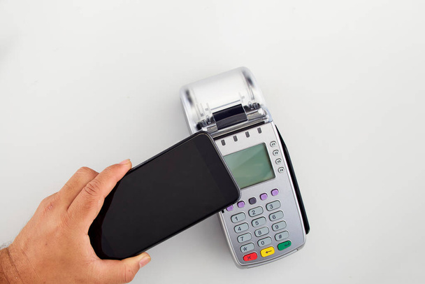 Mannen hand houdt rode credit card naar terminal op witte achtergrond bovenaanzicht kopieerruimte - Foto, afbeelding
