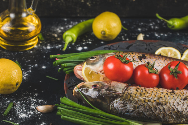 Syrové ryby připravené na vaření s bylinkami, kořením, rajčaty a citronem v dekorativním podnose - Fotografie, Obrázek
