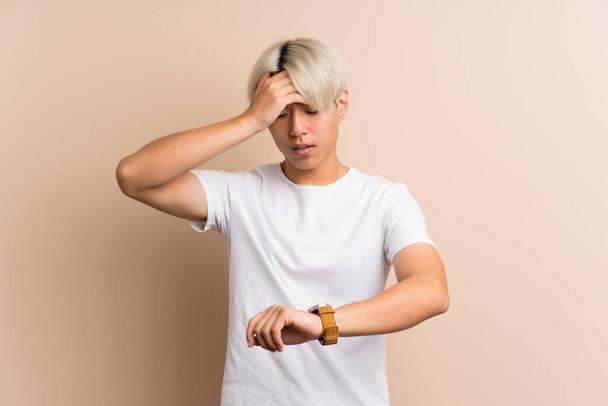 Young asian man over isolated background with wrist watch and surprised - Foto, Imagem