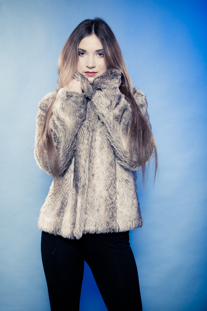 Young woman with long hair in fur coat on blue. - Foto, afbeelding