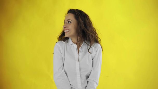 Beautiful woman is looking to right and smiling on yellow background - Fotografie, Obrázek