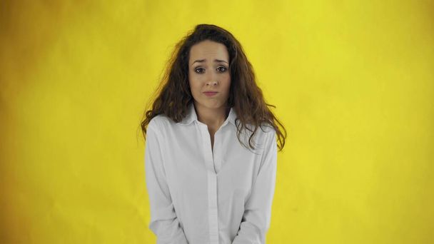 Confused beautiful Caucasian female with long brown hair standing over yellow background - Фото, изображение