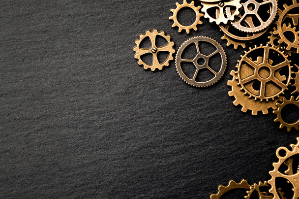 Steampunk accessories and old technology conceptual idea with border made of a group brass cog wheels on dark texture background with copy space - Foto, Imagem
