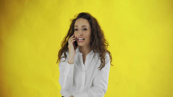 Serious business woman talking mobile phone on yellow background. Portrait of young businesswoman calling phone in studio. Female professional have mobile conversation on smartphone - Φωτογραφία, εικόνα
