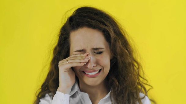 Θλιβερή όμορφη γυναίκα κλαίει στην κάμερα σε κίτρινο φόντο - Φωτογραφία, εικόνα