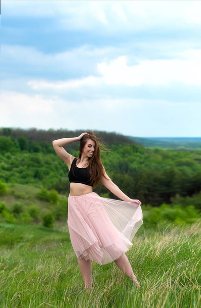 Beautiful girl in pink skirt posing on natural landscape. Young woman relaxing - Zdjęcie, obraz