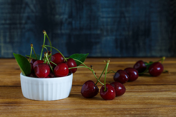 Fresh cherry on plate on wooden blue background. - Foto, afbeelding