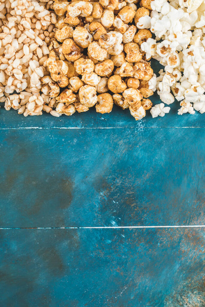 Popcorn and wheat corns on the blue table - Foto, afbeelding