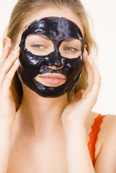 Young woman with carbo black peel-off mask on her face, cosmetic ready to remove, on white. Teen girl taking care of oily skin. Beauty treatment. Skincare. - Foto, imagen
