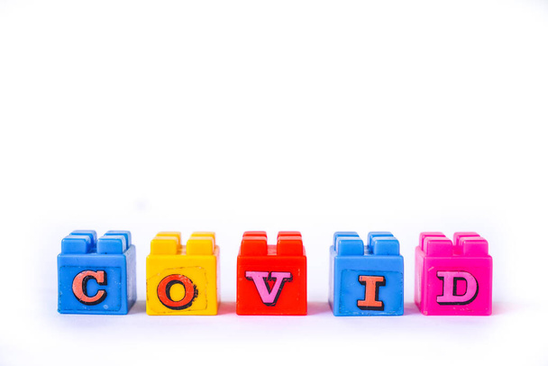 Parole Covid sono disposti in un cubo lego colorato rustico. Adatto ai bambini. Isolato su sfondo bianco
 - Foto, immagini