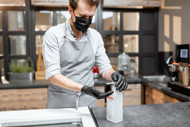 Salesman in protective wear in the cafe during a pandemic - Foto, Bild