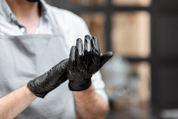 Verkoper desinfecteert handen in een winkel of café - Foto, afbeelding