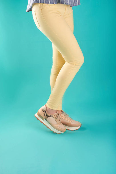 Close up foto de tênis e jeans skinny amarelo contra um fundo de aqua em um estúdio
. - Foto, Imagem