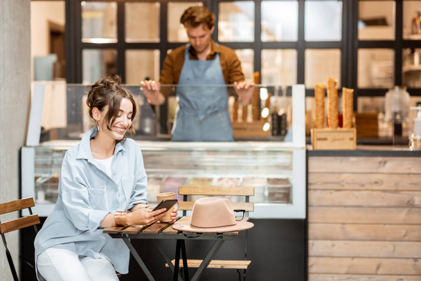 Woma im Café mit einer Verkäuferin im Hintergrund - Foto, Bild