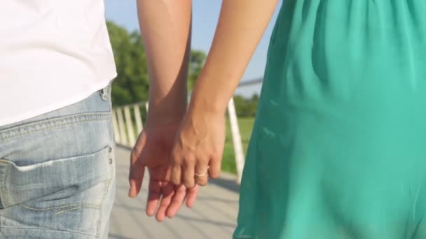 Az eljegyzési gyűrűjét viselő nő fogja a vőlegénye kezét séta közben. - Felvétel, videó