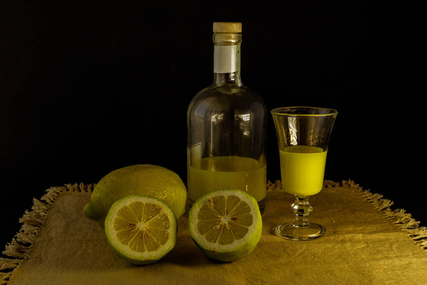 limoncello παραδοσιακό ιταλικό λικέρ λεμονιού με μπουκάλι, ποτήρι και φρέσκο λεμόνι - Φωτογραφία, εικόνα