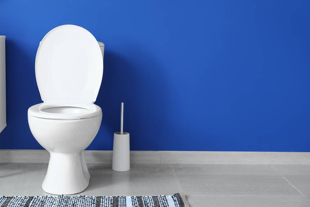 Сучасний унітаз біля кольорової стіни в туалеті
 - Фото, зображення