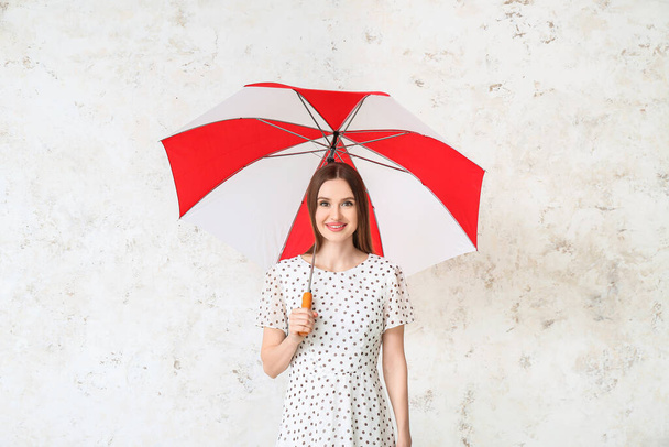Beautiful woman with umbrella on light background - Photo, Image