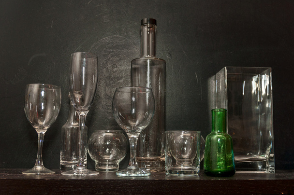 Stilleven met glazen fles en vaas op een donkere achtergrond - Foto, afbeelding