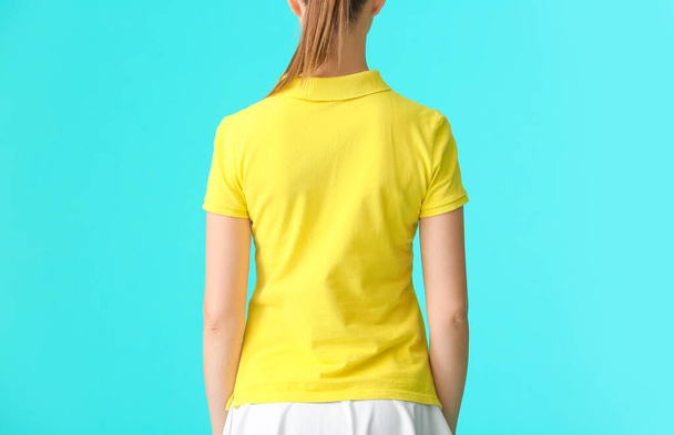Beautiful young woman in stylish polo shirt on color background, back view - Valokuva, kuva