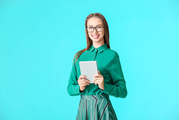 Beautiful young woman in stylish shirt and with tablet on color background - Valokuva, kuva