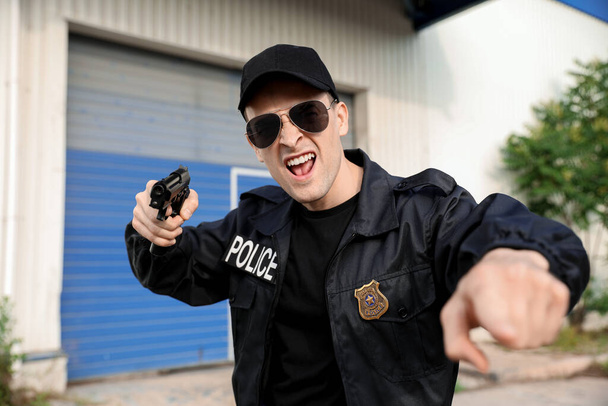 Aggressive police officer with gun outdoors - 写真・画像
