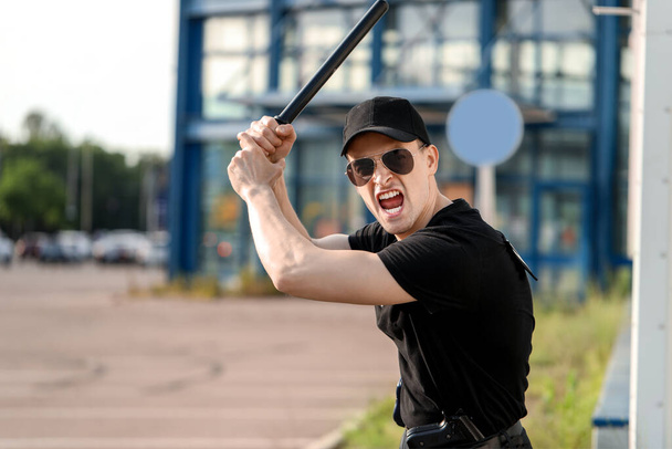 Oficial de policía agresivo con bastón al aire libre
 - Foto, imagen