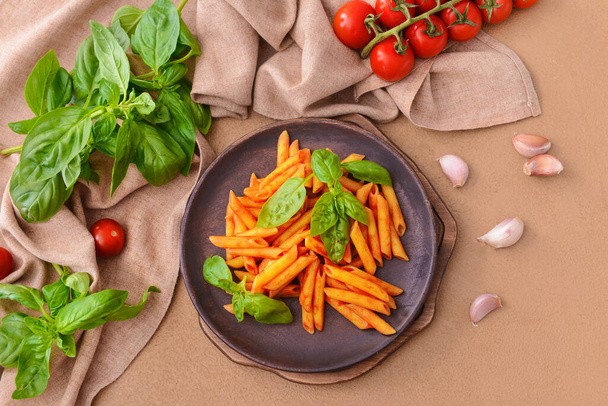 Plato con sabrosa pasta, albahaca y salsa de tomate sobre fondo de color
 - Foto, imagen