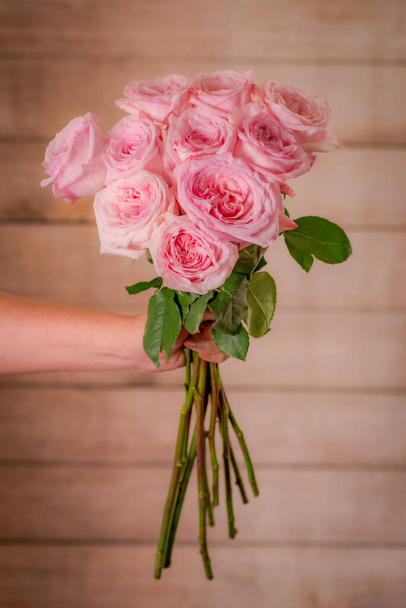 Women hand holding a bouquet of Pink Ohara roses variety, studio shot, pink flowers - Фото, зображення